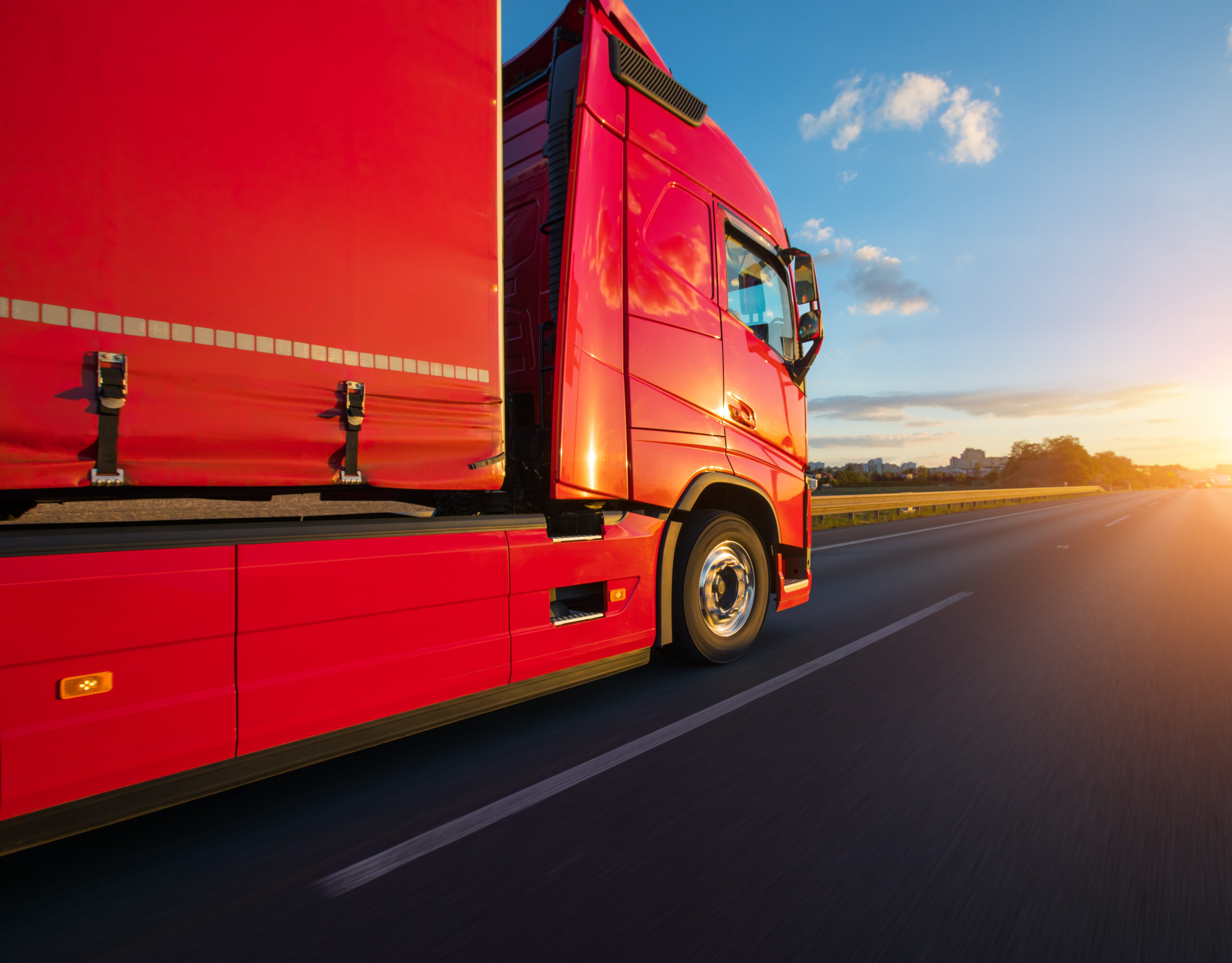 Roter LKW fährt richtung Sonnenuntergang