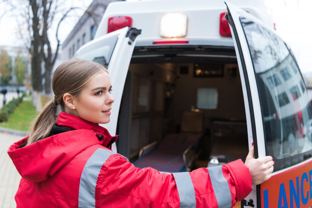 Junge Ärztin öffnet Krankenwagentüren - Tourenplanung in der ambulanten Pflege