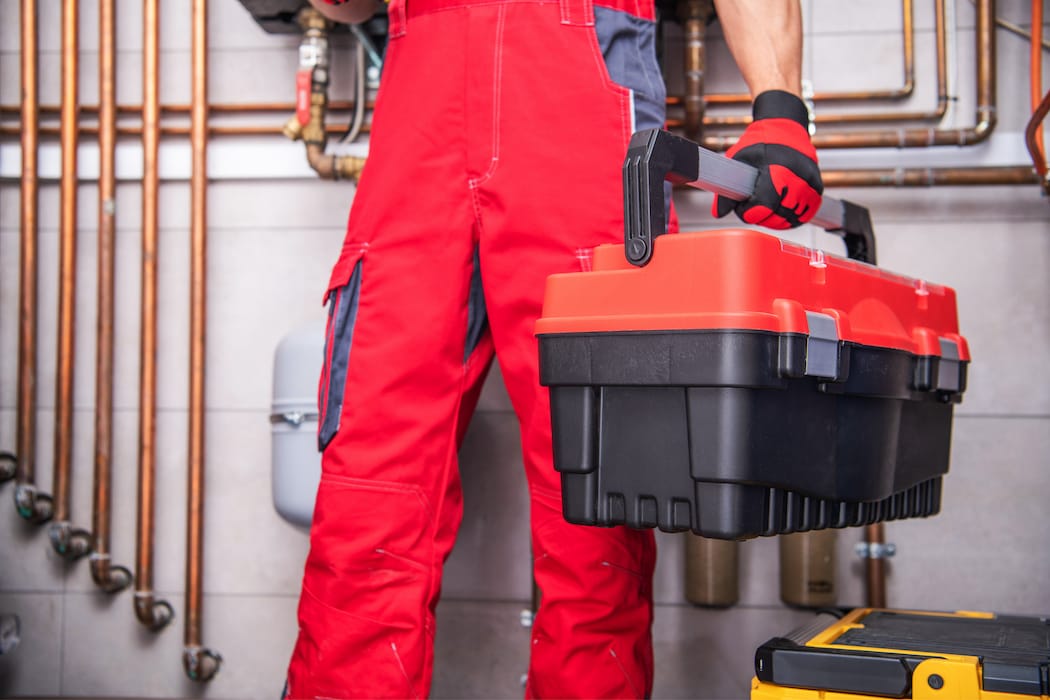 Handwerker der einen Werkzeugkoffer in der Hand hält