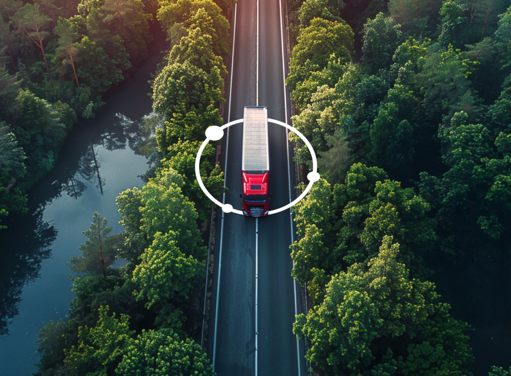 Ein roter Lastwagen fährt auf einer Straße durch den Wald, umringt von der routecontrol Bildmarke